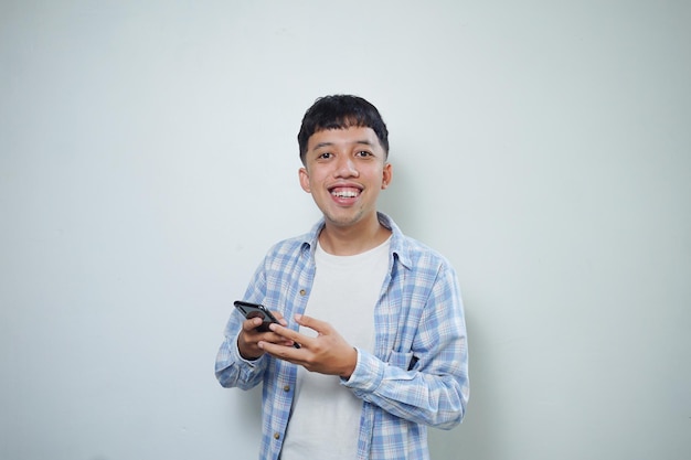 Uśmiechnięty azjatycki mężczyzna wyraz twarzy za pomocą telefonu komórkowego, patrząc na kamery