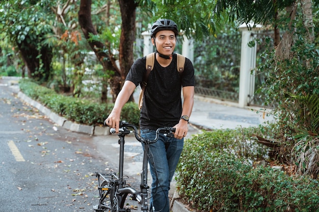 Uśmiechnięty azjatykci młodego człowieka odprowadzenie z falcowanie rowerem