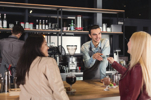 Uśmiechnięty barista biorąc kartę kredytową od klientów, aby zapłacić za napój w kasie kawiarni. Mały biznes, ludzie zawód, koncepcja płatności i usług, miejsce kopiowania
