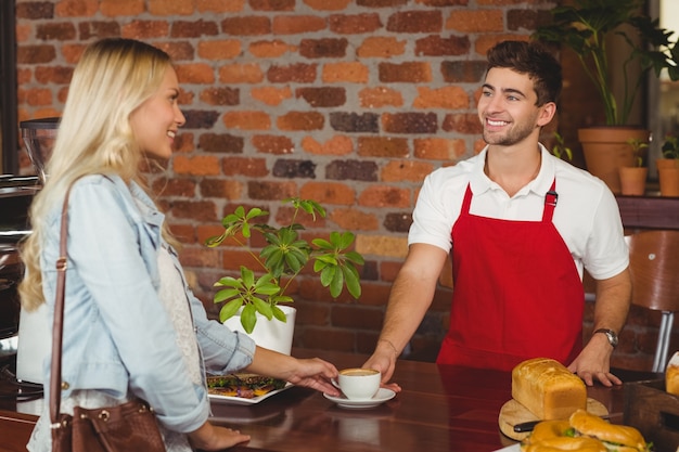 Uśmiechnięty barista obsługujących klienta