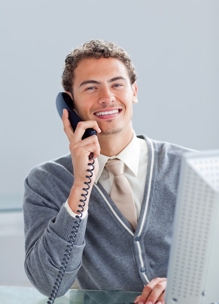 Uśmiechnięty biznesmen na telefonie przy jego biurkiem