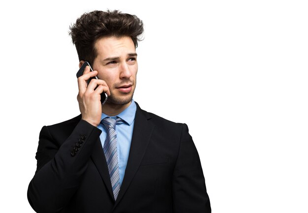 Uśmiechnięty biznesmen opowiada przy telefonem odizolowywającym na bielu