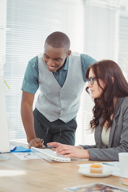 Uśmiechnięty Biznesmen Patrzeje Komputer Podczas Gdy Dyskutujący Z Coworker