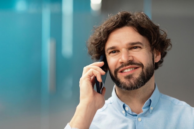 Uśmiechnięty biznesmen pracujący i rozmawiający przez telefon w biurze