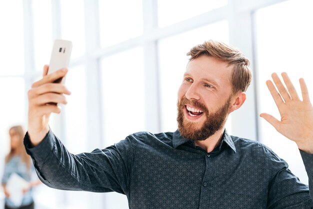 Uśmiechnięty biznesmen rozmawia przez czat wideo na swoim smartfonie