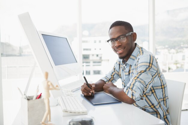 Uśmiechnięty biznesmen używa digitizer przy biurkiem