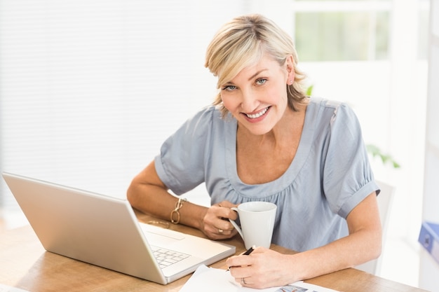 Uśmiechnięty bizneswoman pracuje na laptopie