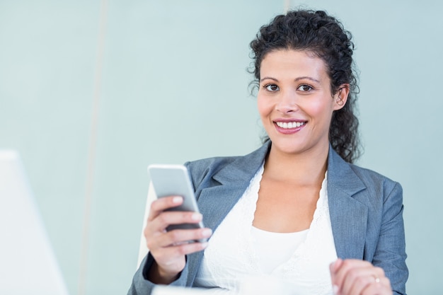 Uśmiechnięty bizneswoman używa mądrze telefon