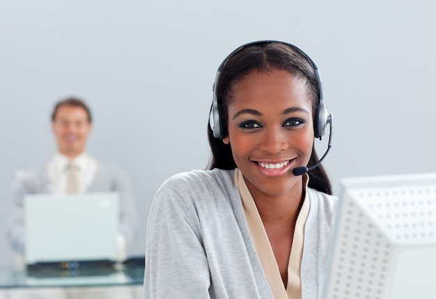 Uśmiechnięty bizneswoman używa słuchawki przy jej biurkiem