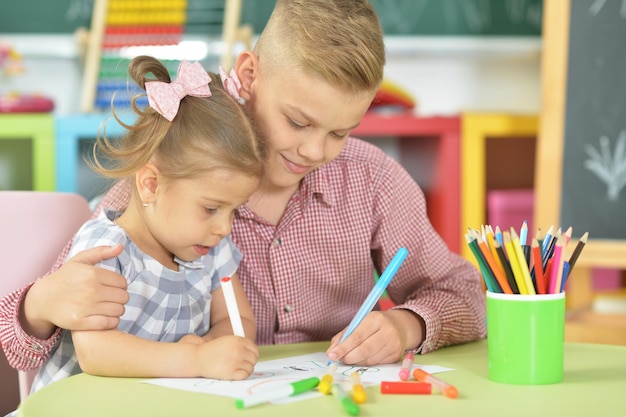 Uśmiechnięty brat i siostra rysujący pisakami