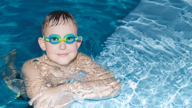 Uśmiechnięty chłopiec pływa w basenie Sport i rekreacja Piękni ludzie