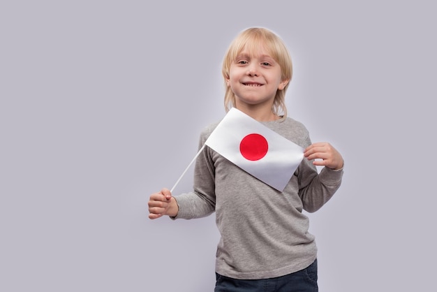Uśmiechnięty chłopiec z flagą Japonii w rękach Edukacja w Japonii Nauka japońskiego dla dzieci