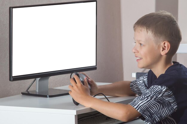 Uśmiechnięty chłopiec z gamepadem i komputerem grającym w gry wideo w domu