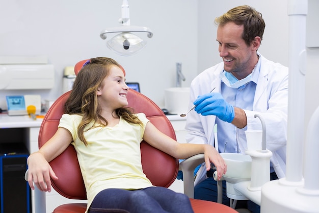 Uśmiechnięty dentysta mówi do młodego pacjenta