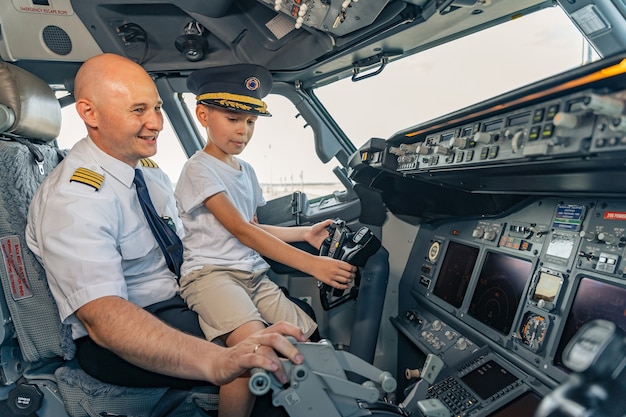 Uśmiechnięty dojrzały pilot i dzieciak siedzący w kabinie