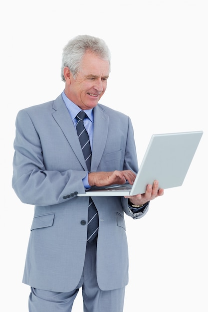 Uśmiechnięty dojrzały tradesman pracuje na jego laptopie