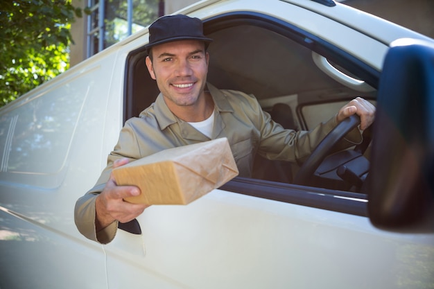 Uśmiechnięty doręczeniowy mężczyzna siedzi w jego samochodzie dostawczym