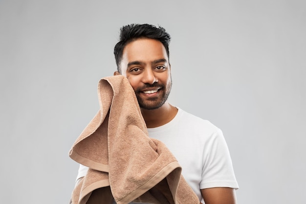 Uśmiechnięty Indianin z ręcznikiem na szarym tle