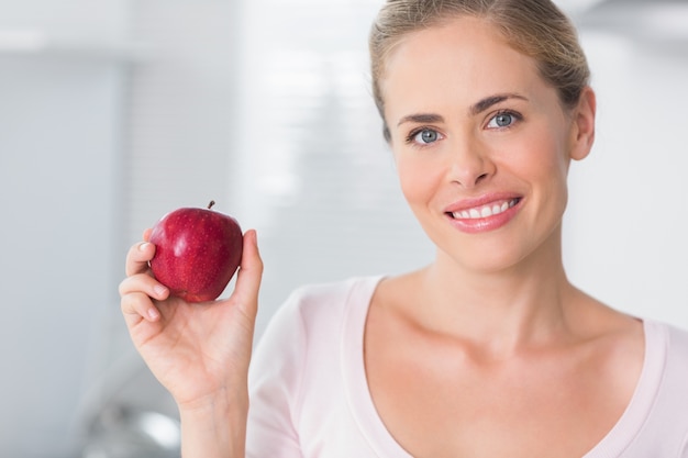 Uśmiechnięty kobiety mienia jabłko w prawej ręce