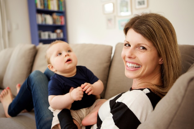 Uśmiechnięty macierzysty obsiadanie na kanapie w domu z jej synem