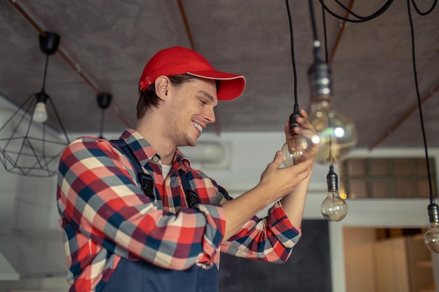 Uśmiechnięty mechanik zmienia żarówkę elektryczną w pomieszczeniu