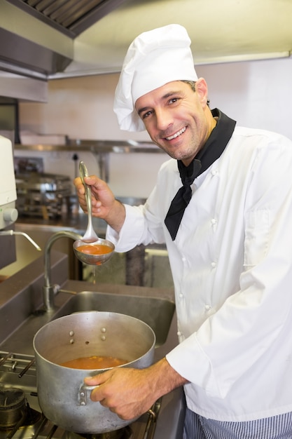 Uśmiechnięty męski szefa kuchni narządzania jedzenie w kuchni