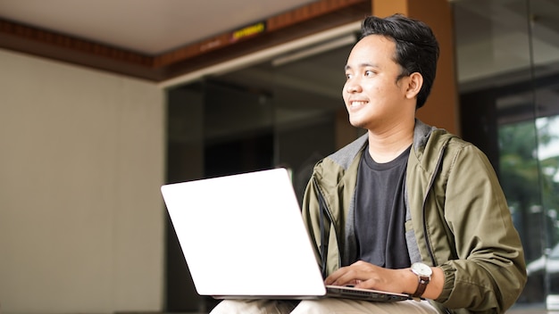 Uśmiechnięty mężczyzna Azji w plecaku z laptopem