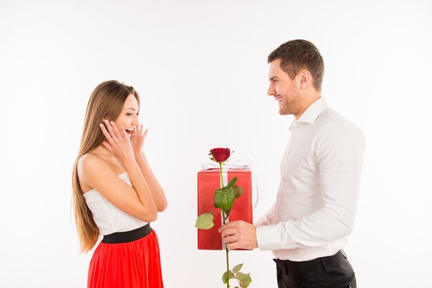 Uśmiechnięty mężczyzna daje prezent i różę swojej dziewczynie