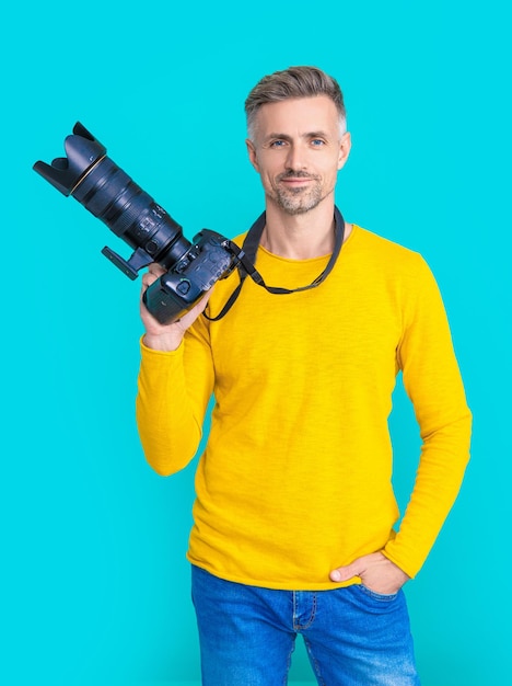 Uśmiechnięty mężczyzna fotograf z aparatem samodzielnie na niebieski Mężczyzna fotograf z aparatem