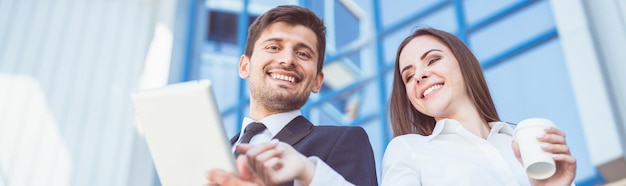 Zdjęcie uśmiechnięty mężczyzna i kobieta stoją z tabletem na tle budynku