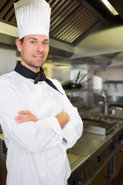 Zdjęcie uśmiechnięty mężczyzna kucharz z rękami krzyżował w kuchni