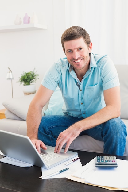 Uśmiechnięty mężczyzna na laptopie w domu