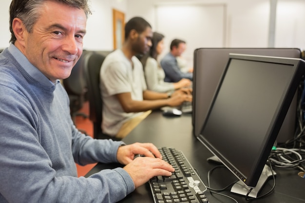 Uśmiechnięty mężczyzna obsiadanie przed komputerem