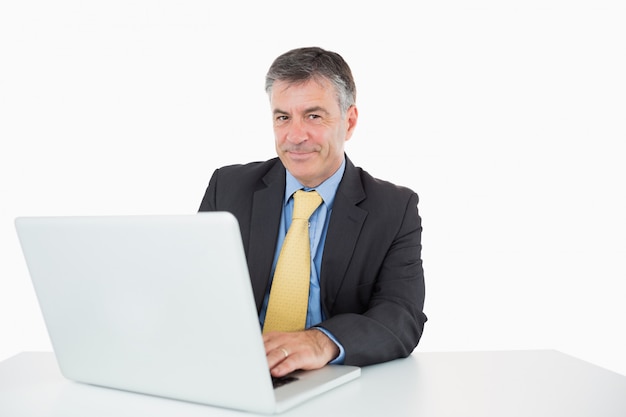 Uśmiechnięty mężczyzna pisać na jego laptopie