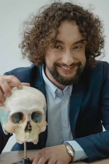 Zdjęcie uśmiechnięty mężczyzna pozujący z ludzką czaszką
