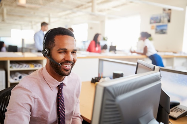 Uśmiechnięty mężczyzna pracownik call center patrzący na zbliżenie ekranu