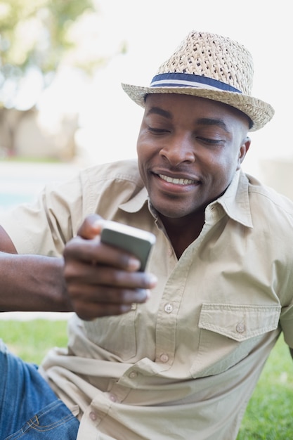 Uśmiechnięty mężczyzna relaksuje w jego ogródzie texting na telefonie