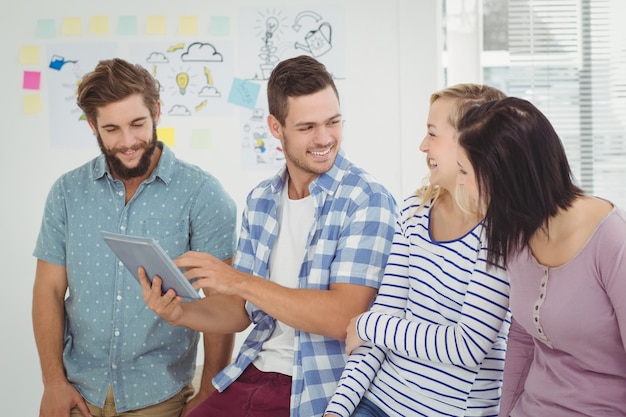 Uśmiechnięty mężczyzna trzyma cyfrową pastylki pozycję z coworkers