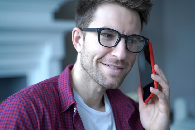 Zdjęcie uśmiechnięty mężczyzna w okularach trzymający czerwony smartfon szczęśliwie łączący się