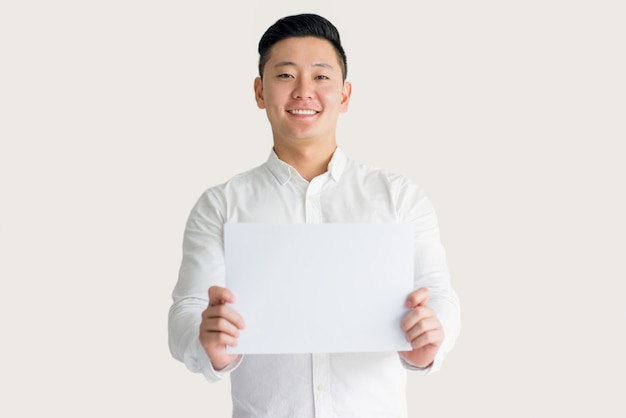 Uśmiechnięty Młody Azjatycki mężczyzna seansu papier przy kamerą