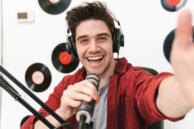 Uśmiechnięty młody człowiek radiowy nagrywający podcast do programu online