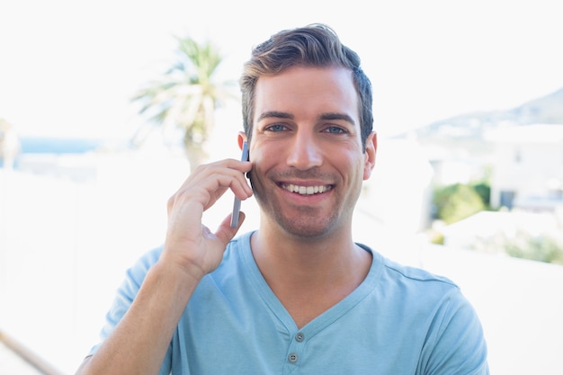 Uśmiechnięty młody człowiek używa telefon komórkowego