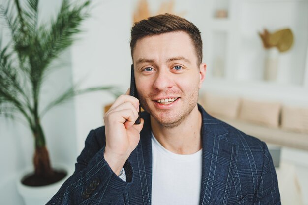 Uśmiechnięty młody człowiek w kurtce rozmawia przez telefon Emocje śmiechu z rozmowy przez telefon Udany człowiek pracuje zdalnie przez telefon