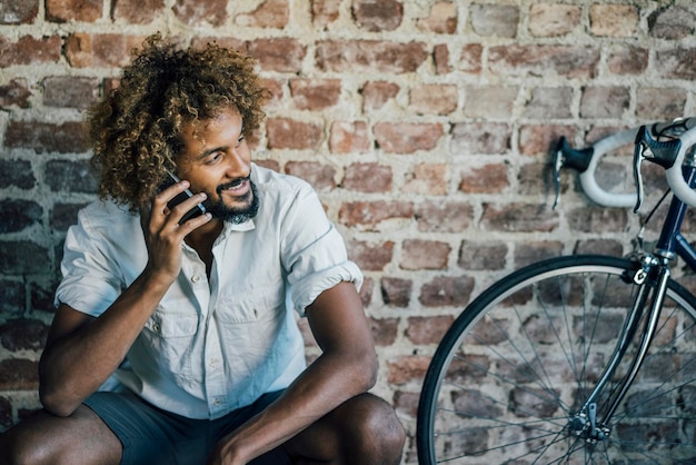 Uśmiechnięty młody człowiek z bicyklem na telefonie komórkowym