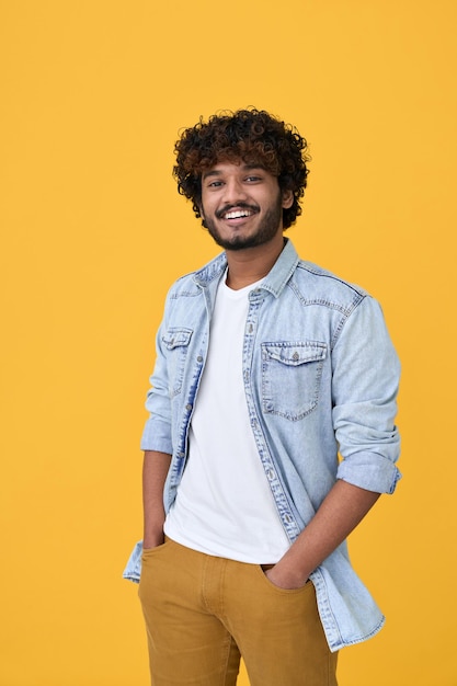 Zdjęcie uśmiechnięty młody indyjski facet stojący na białym tle na żółtym tle vertical