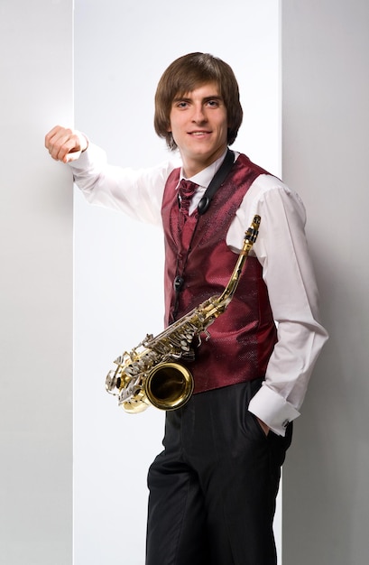 uśmiechnięty młody mężczyzna w garniturze z saksofonem na białym tle