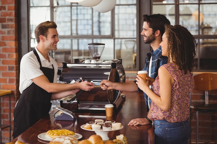 Zdjęcie uśmiechnięty modniś daje kredytowej karcie barista