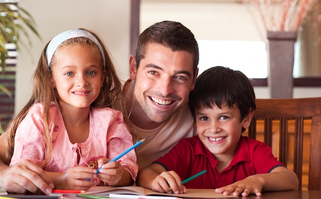 Uśmiechnięty ojciec pomaga jego dzieciom na pracę domową