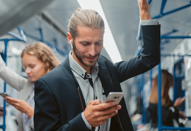 Uśmiechnięty pasażer czytający wiadomość na swoim smartfonie. ludzie i technologia.