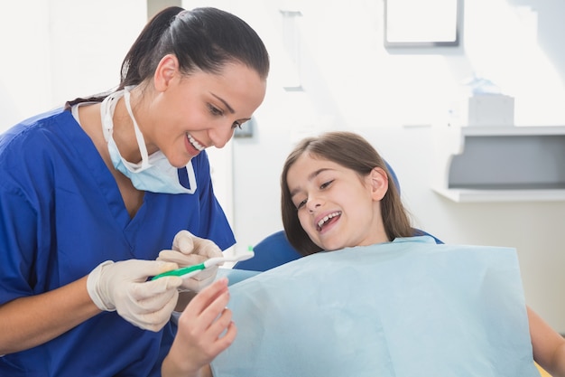 Uśmiechnięty pediatryczny dentysta wyjaśnia młody pacjent toothbrush